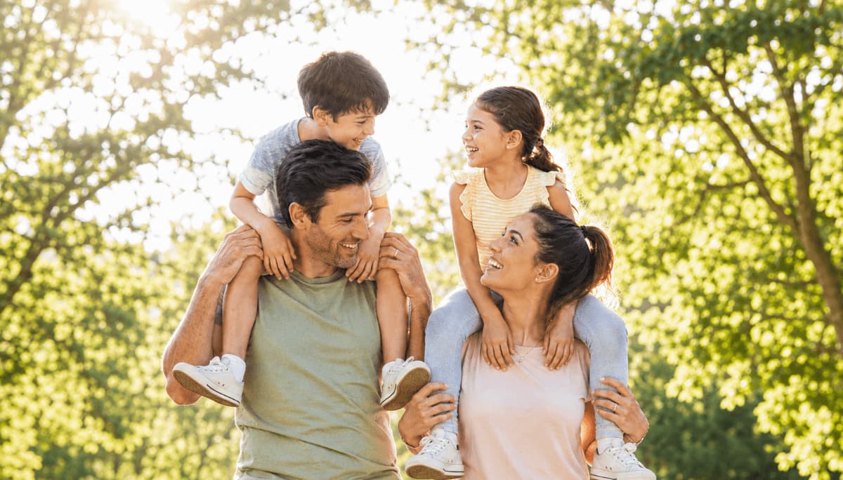 Family with a young child outdoors on a sunny day, illustrating people who may be more sensitive to air pollution near AQI 100.