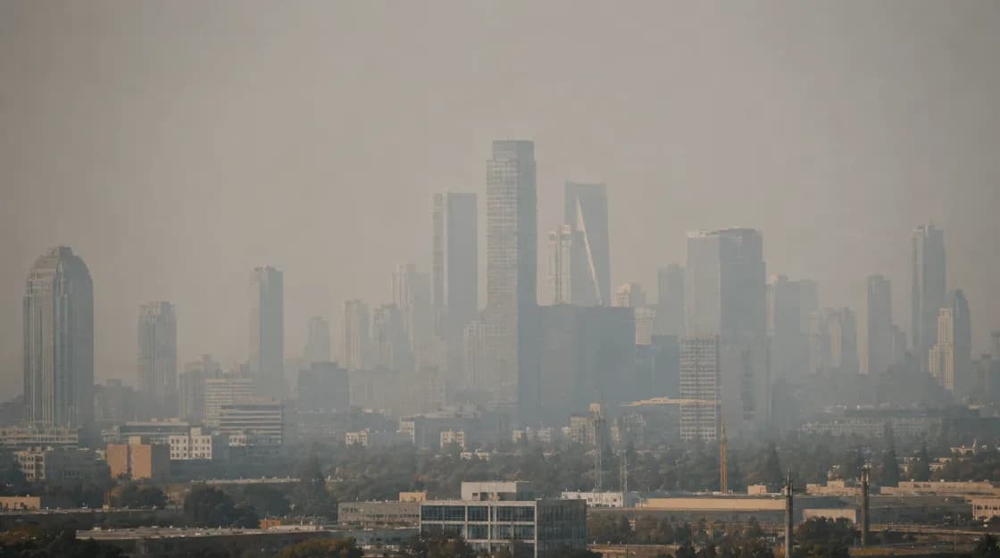 A city skyline obscured by thick haze during a hazardous air quality day.